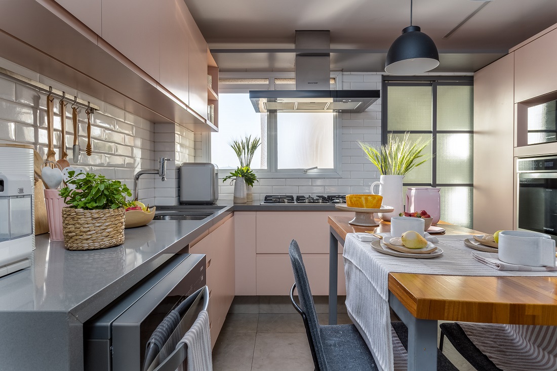 cozinha tem mix de cores com marcenaria rosa e revestimentos em cinza e branco